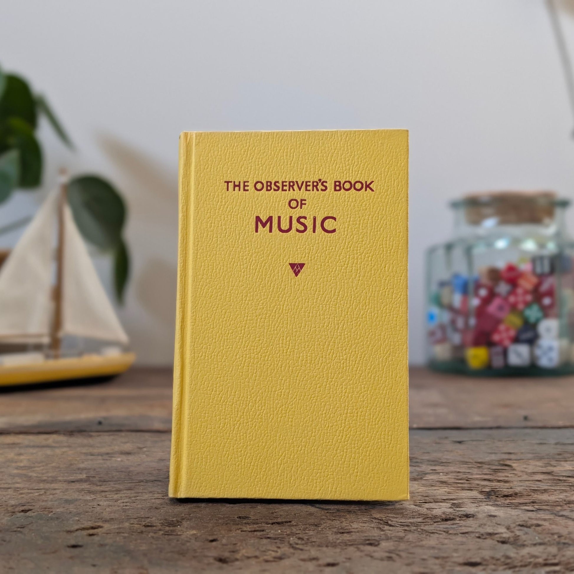 Book titled 'The Observer's Book of' on a wooden surface with decorative items in the background.