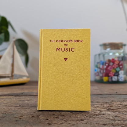 Book titled 'The Observer's Book of' on a wooden surface with decorative items in the background.